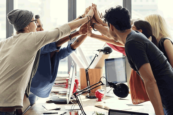 Homepage Agentur Werder - Ein Team hat einen Auftrag abgeschlossen und feiert mit einem Gruppen-High-Five den Erfolg.